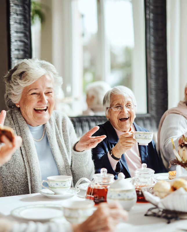 Elderly women laughing at a table